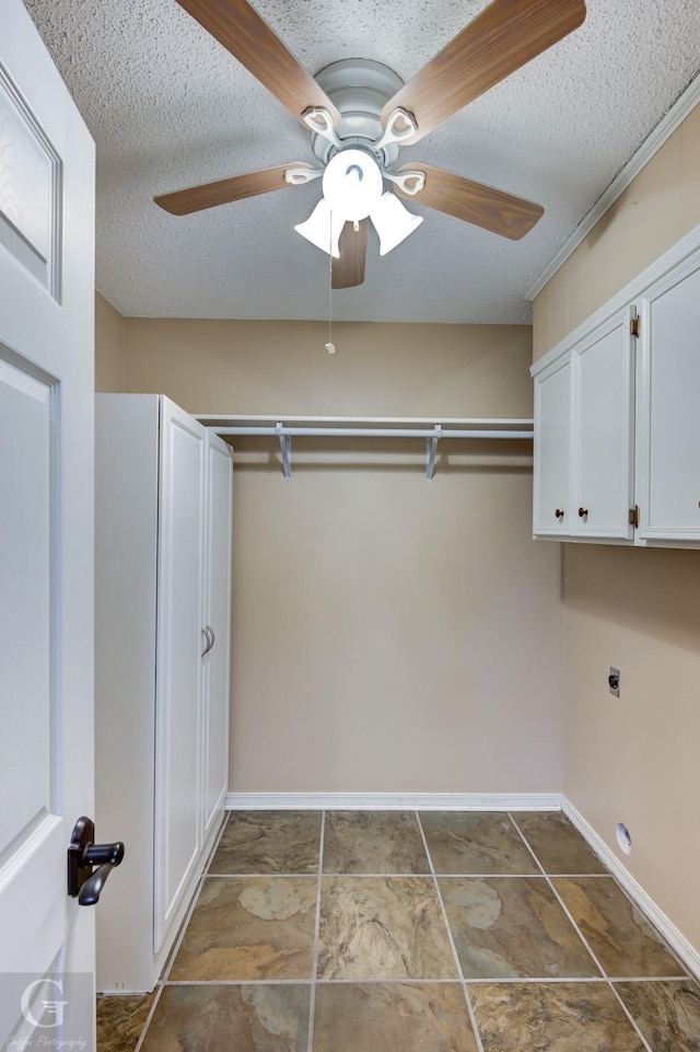 laundry area with a textured ceiling, ceiling fan, cabinets, and electric dryer hookup