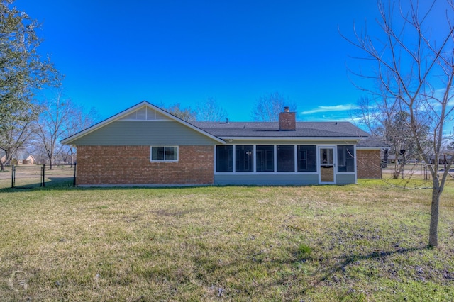 rear view of house featuring a lawn and a sunroom