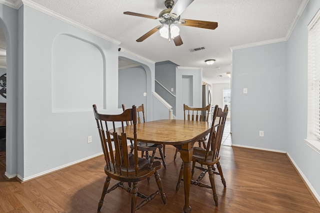 dining space with visible vents, arched walkways, wood finished floors, and ornamental molding