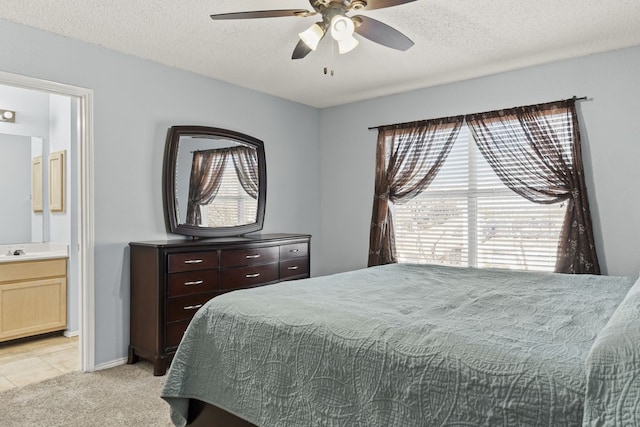 bedroom with light carpet, ensuite bath, a textured ceiling, a ceiling fan, and a sink