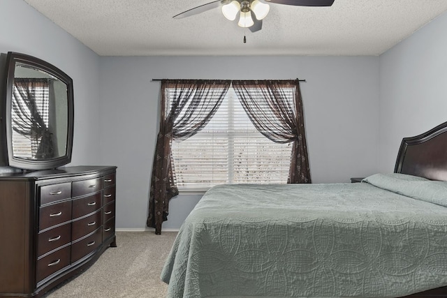 bedroom featuring baseboards, light colored carpet, ceiling fan, and a textured ceiling