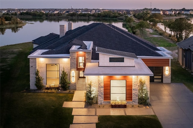 view of front of property with a yard, a garage, and a water view