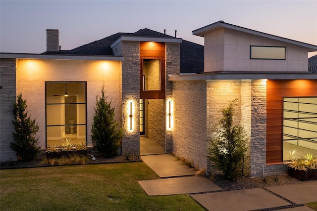 exterior entry at dusk featuring a yard