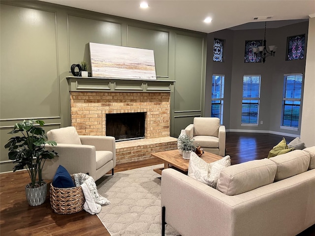 living room with a brick fireplace, a notable chandelier, and hardwood / wood-style floors