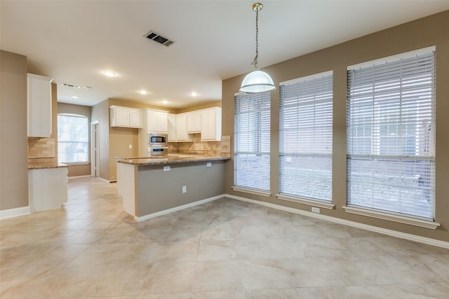 kitchen with kitchen peninsula, decorative light fixtures, white cabinetry, dark stone counters, and appliances with stainless steel finishes