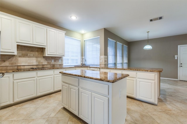 kitchen with a center island, decorative light fixtures, black electric cooktop, white cabinets, and dark stone counters