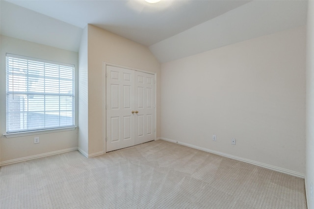 unfurnished bedroom with vaulted ceiling, light carpet, and a closet