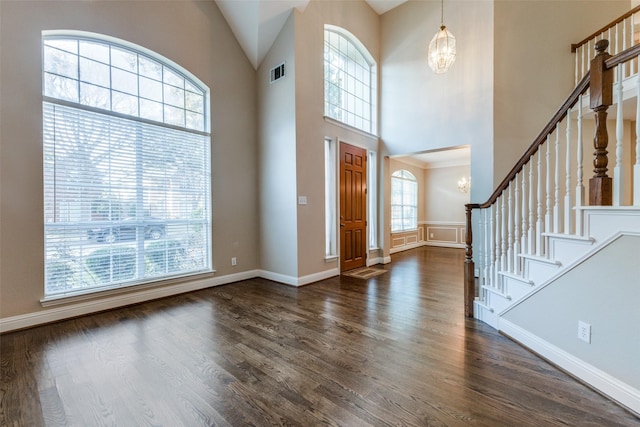 foyer with a healthy amount of sunlight, a notable chandelier, and dark wood-type flooring