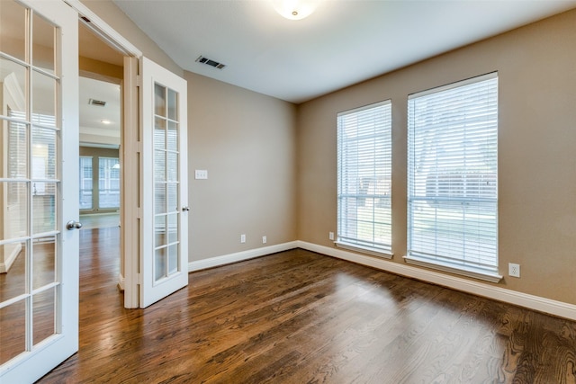 spare room featuring french doors, plenty of natural light, and dark hardwood / wood-style floors