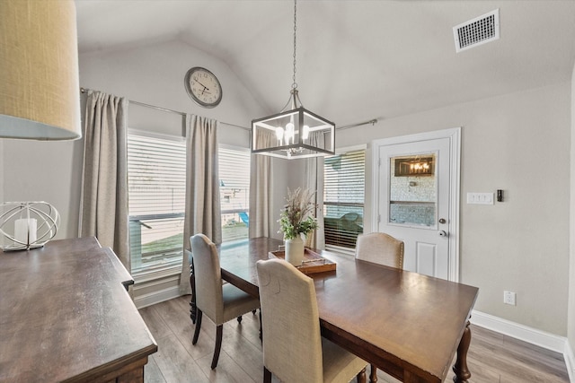 dining area featuring lofted ceiling, a wealth of natural light, a notable chandelier, and wood-type flooring