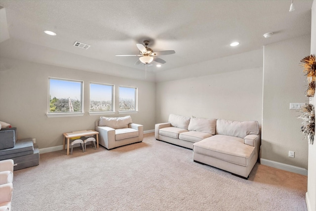 living room featuring light colored carpet, a raised ceiling, and ceiling fan