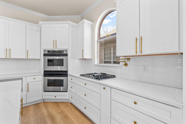 kitchen featuring stainless steel appliances, white cabinetry, and light stone counters