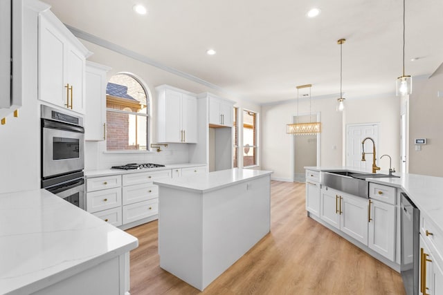 kitchen with sink, stainless steel appliances, white cabinetry, decorative backsplash, and hanging light fixtures