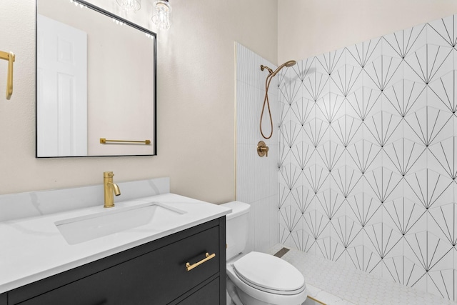 bathroom featuring a tile shower, vanity, and toilet