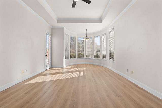 unfurnished room featuring ceiling fan with notable chandelier, a raised ceiling, light hardwood / wood-style floors, and crown molding