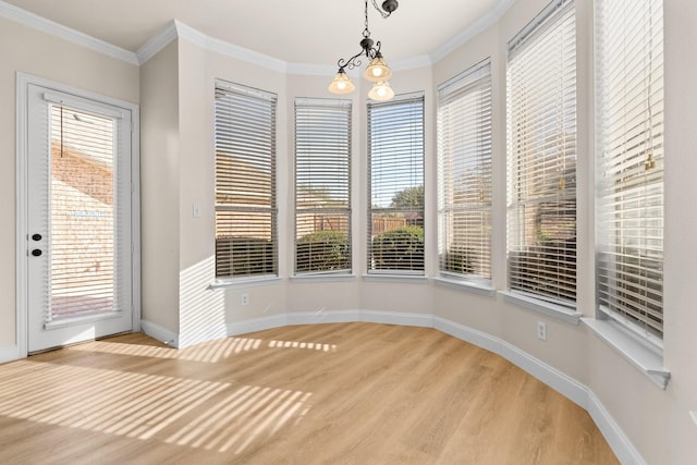 unfurnished dining area with hardwood / wood-style floors, an inviting chandelier, ornamental molding, and plenty of natural light