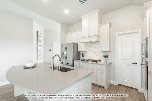 kitchen featuring appliances with stainless steel finishes, white cabinets, a center island with sink, and sink