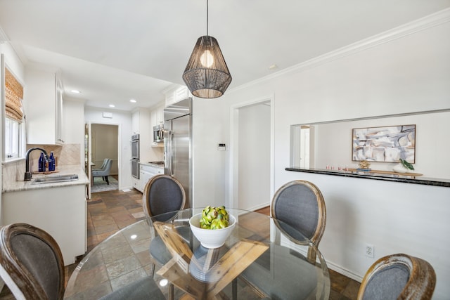 dining room featuring sink and crown molding