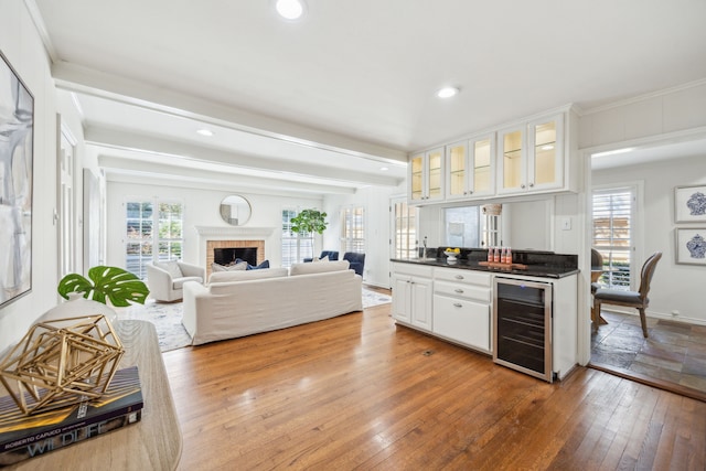 kitchen with white cabinets, a fireplace, light hardwood / wood-style floors, wine cooler, and beam ceiling