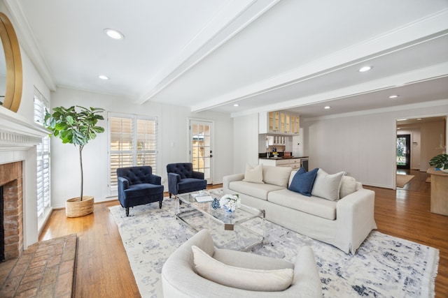 living room with a fireplace, beam ceiling, light hardwood / wood-style flooring, and a healthy amount of sunlight