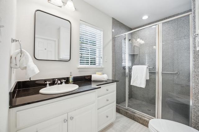 bathroom featuring a shower with shower door, vanity, and toilet