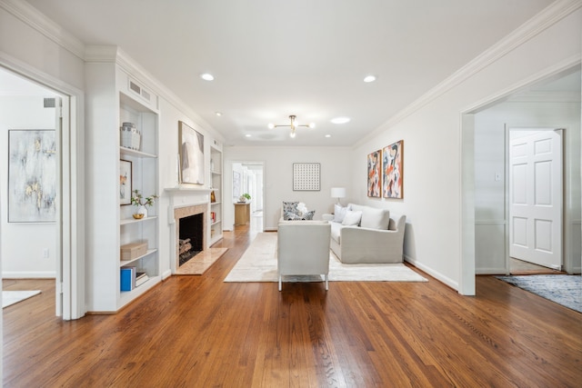 unfurnished living room with crown molding, built in shelves, and hardwood / wood-style flooring