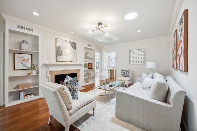 living room featuring a chandelier, hardwood / wood-style floors, built in shelves, and crown molding