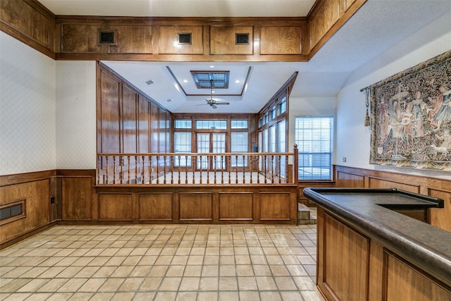 interior space featuring brown cabinetry, dark countertops, a wainscoted wall, and ceiling fan