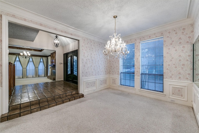 interior space featuring wallpapered walls, ornamental molding, an inviting chandelier, a textured ceiling, and carpet floors