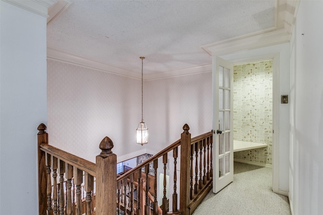 corridor with crown molding, an upstairs landing, and wallpapered walls