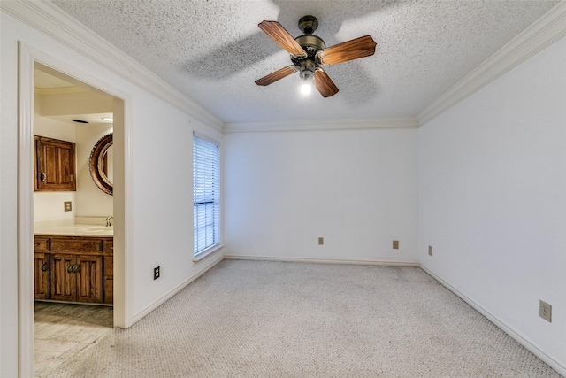 carpeted empty room featuring crown molding, ceiling fan, sink, and a textured ceiling