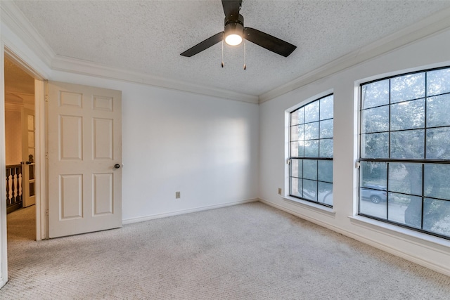 carpeted spare room featuring baseboards, ceiling fan, ornamental molding, and a textured ceiling