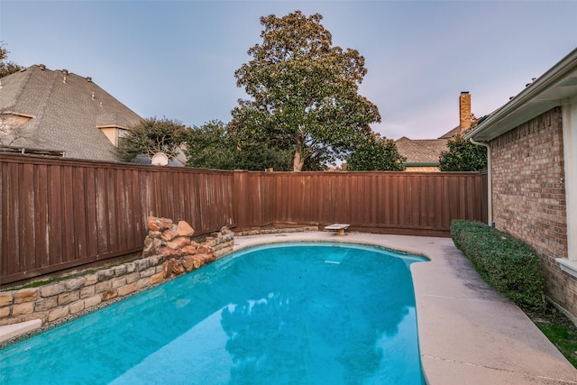 view of pool with a fenced backyard and a diving board