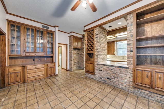 kitchen featuring a textured ceiling, brick wall, ornamental molding, and visible vents