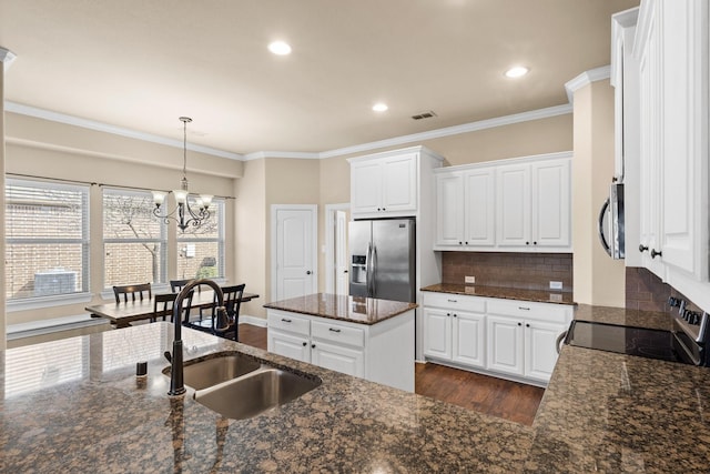 kitchen featuring decorative light fixtures, a kitchen island, white cabinets, appliances with stainless steel finishes, and sink