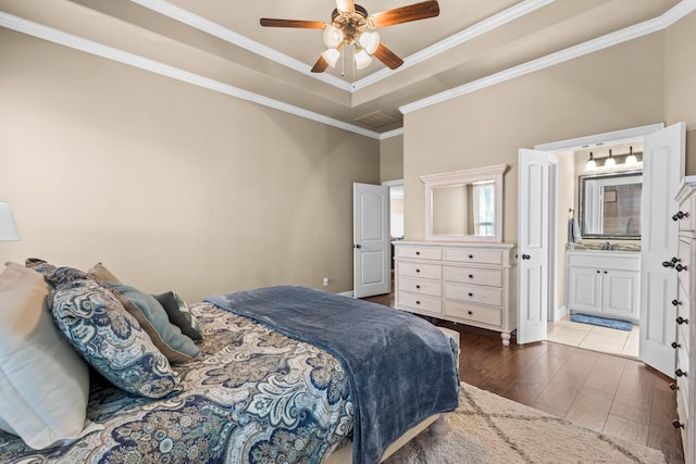 bedroom featuring ensuite bathroom, hardwood / wood-style floors, a tray ceiling, ornamental molding, and ceiling fan