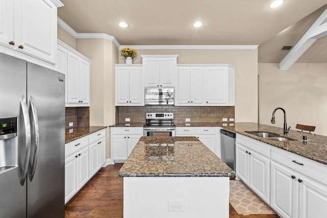 kitchen with stainless steel appliances, tasteful backsplash, white cabinets, dark stone counters, and sink