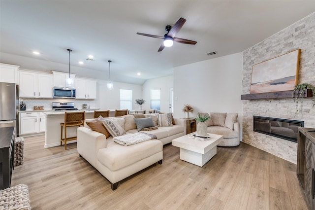 living room with ceiling fan, light hardwood / wood-style flooring, and a fireplace