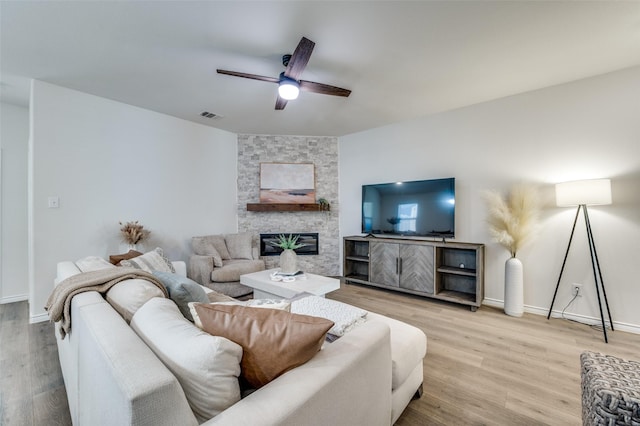 living room featuring a fireplace, ceiling fan, and light hardwood / wood-style floors