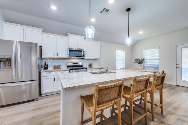 kitchen with sink, a kitchen island with sink, pendant lighting, and appliances with stainless steel finishes