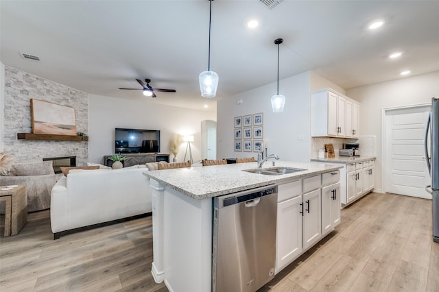 kitchen featuring light stone counters, a center island with sink, white cabinetry, appliances with stainless steel finishes, and sink