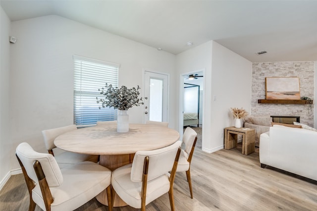 dining space featuring a brick fireplace, ceiling fan, and light hardwood / wood-style flooring