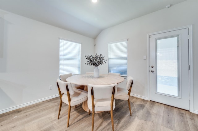 dining area featuring light wood-type flooring and vaulted ceiling