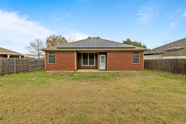 back of house with a lawn, central air condition unit, and solar panels