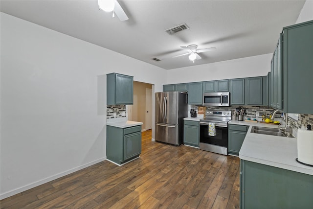 kitchen with dark hardwood / wood-style floors, backsplash, appliances with stainless steel finishes, ceiling fan, and sink