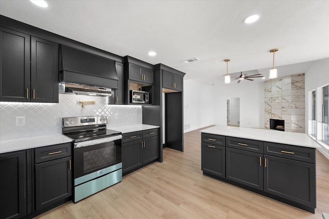 kitchen with hanging light fixtures, light wood-type flooring, a fireplace, appliances with stainless steel finishes, and ceiling fan