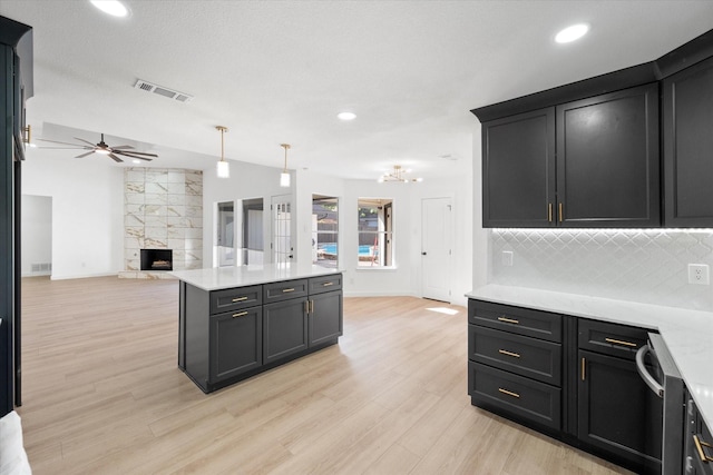 kitchen with decorative light fixtures, a tile fireplace, light hardwood / wood-style floors, and tasteful backsplash