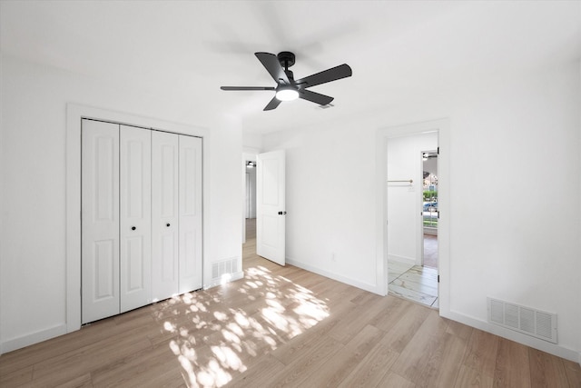 unfurnished bedroom with light wood-type flooring, ceiling fan, and a closet