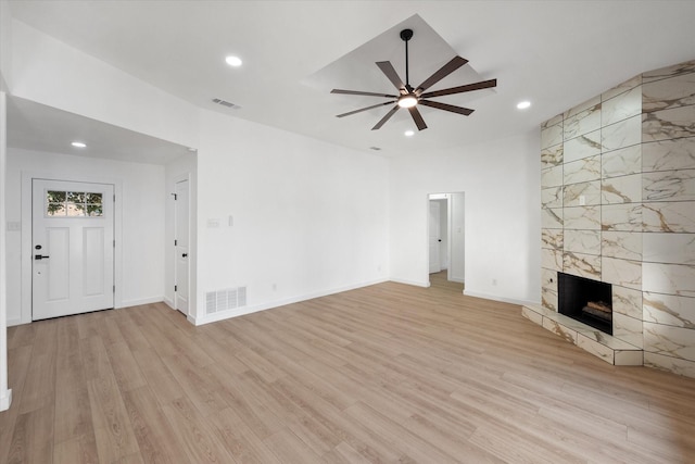 unfurnished living room featuring a tile fireplace, ceiling fan, and light wood-type flooring