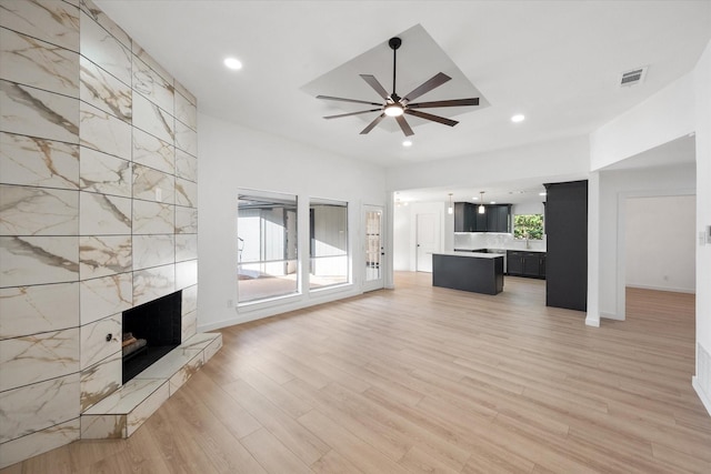 unfurnished living room featuring ceiling fan, a healthy amount of sunlight, light hardwood / wood-style flooring, and a fireplace